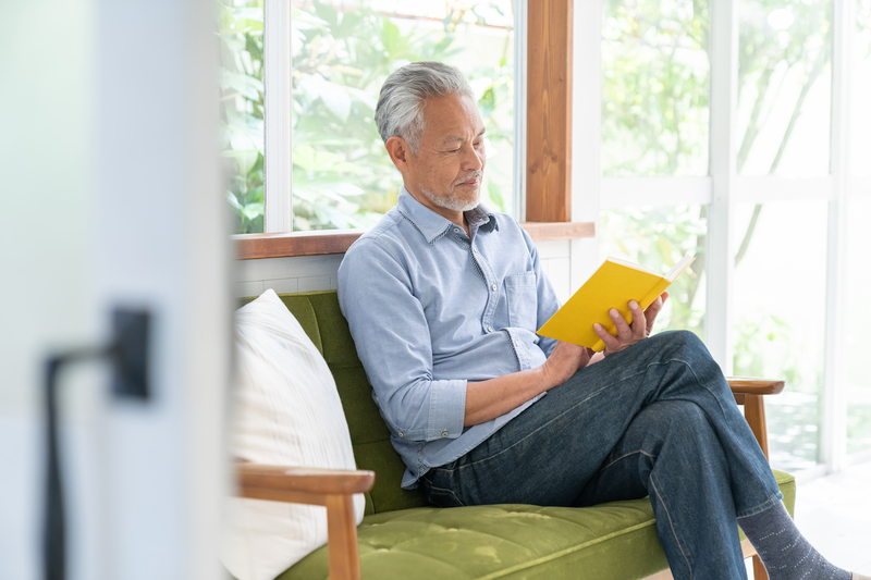 elderly_man_reading_book_sofa.png