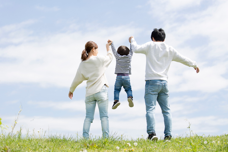 family_lifting_child_outdoors.png